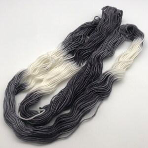 May include: A skein of yarn with a gradient color transition from white to dark gray.