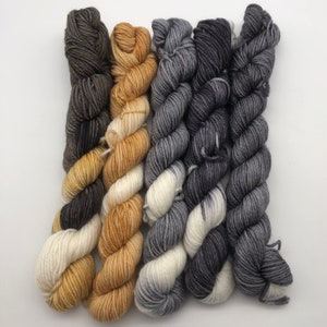 May include: Five skeins of yarn in different colors. Two skeins are a gradient of brown to white, two skeins are a gradient of gray to white, and one skein is a gradient of brown to gold.