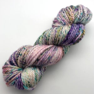 Könnte beinhalten: Eine Garnrolle in einem helllila, weißen und grünen Farbverlauf mit Farbflecken.