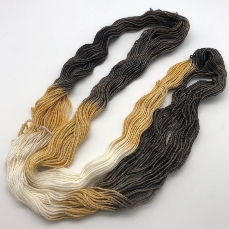 May include: A skein of yarn with a gradient of white, yellow, and brown colors.