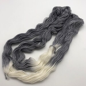 May include: A skein of yarn with a gradient color transition from white to gray.