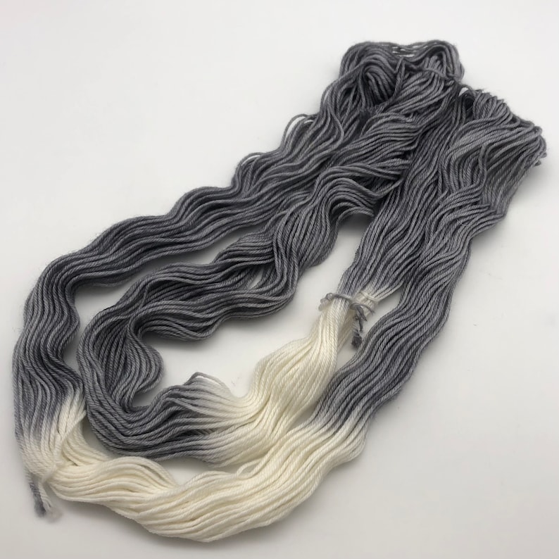 May include: A skein of yarn with a gradient color transition from white to gray.
