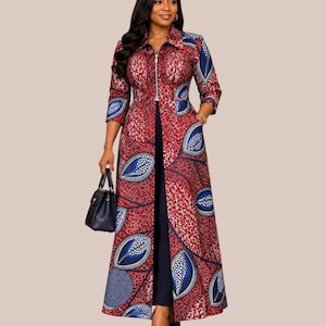 May include: A long-sleeved, floor-length duster coat featuring a vibrant red and blue leaf-patterned print with a white speckled texture. The garment has a collared neckline, a full-length front zipper closure, and is worn over solid black trousers.