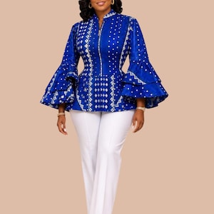 May include: A vibrant blue long-sleeved top featuring a white geometric pattern, a front zipper closure, and tiered bell sleeves, paired with solid white trousers. The top has a structured fit with a high collar and a flared peplum-style waistline.