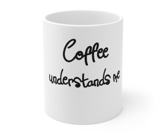 Op de afbeelding: Witte keramische koffiemok met zwarte tekst die "Coffee understands me" luidt.