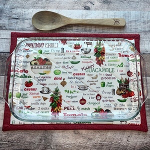 May include: A glass baking dish with a red and white quilted hot pad. The hot pad has a pattern of various food items and recipes, including "Brown Boy Chili", "Salsa", and "Kickin' Guacamole".