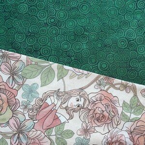 May include: Two fabric patterns are shown. The top fabric is dark green with a repeating circular design. The bottom fabric has a floral pattern with a woman in a pink dress surrounded by roses and other flowers. The background is off-white.