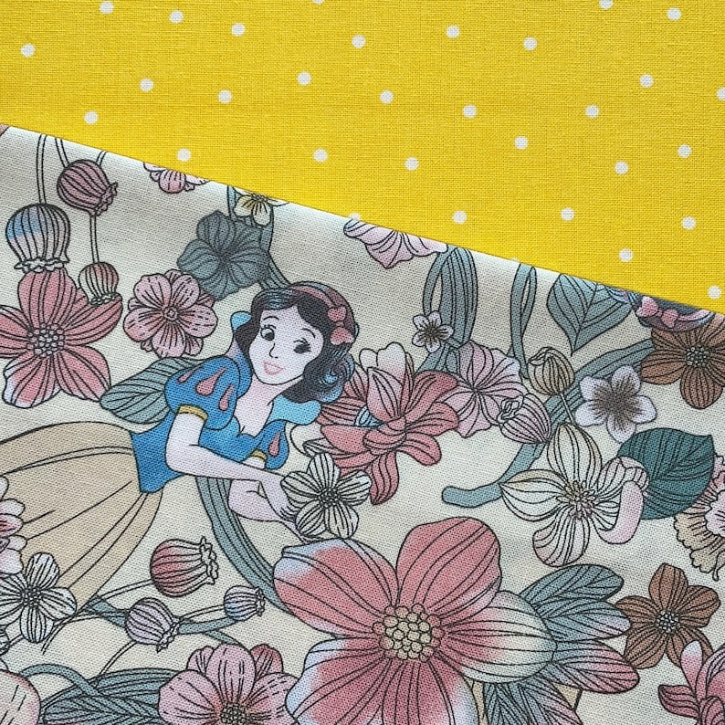May include: A fabric design featuring a cartoon illustration of Snow White surrounded by pink and beige flowers. The design is set against a yellow background with white polka dots.