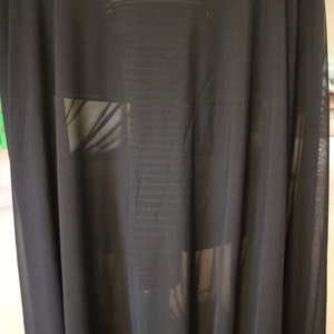 May include: Black sheer fabric draped over a chair. The fabric is translucent, allowing the chair to be seen through it.