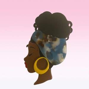 May include: A black and brown profile silhouette of a woman with a blue and white patterned headscarf and a yellow earring.