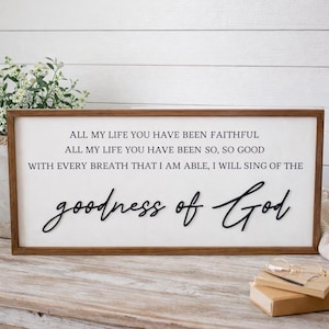 May include: A rectangular wooden sign with a white background and brown frame. The sign features black text that reads "ALL MY LIFE YOU HAVE BEEN FAITHFUL...goodness of God."