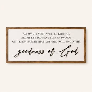 May include: A rectangular wooden framed sign with the words "ALL MY LIFE YOU HAVE BEEN FAITHFUL" and "goodness of God" in black script. The background is white.
