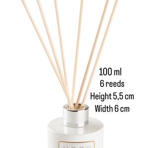 Op de afbeelding: Witte diffuserfles met een zilveren deksel en zes houten rietjes. De fles is gelabeld "MOOD & MOOD" en heeft een capaciteit van 100 ml. De fles is 5,5 cm hoog en 6 cm breed.