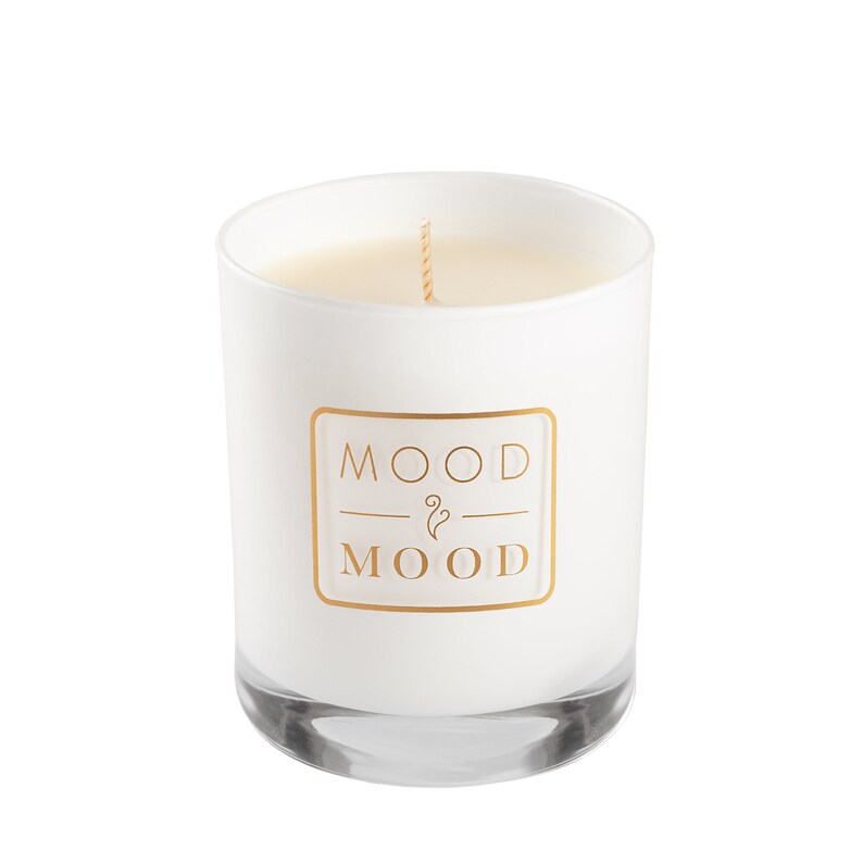 Op de afbeelding: Witte kaars in een glazen pot met een gouden label waarop "MOOD & MOOD" staat.