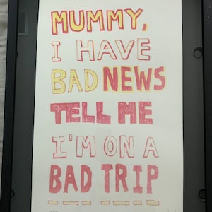 以下が含まれることがあります： 白い背景に赤と黄色の文字で「MUMMY, I HAVE BAD NEWS TELL ME I'M ON A BAD TRIP」と書かれた額装されたプリント。プリントは12/50と番号が付けられ、「fmd 2019」と署名されています。