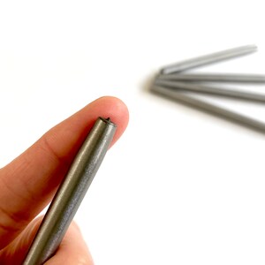 Pu&ograve; includere: Primo piano di un'asta di metallo argentata con una punta appuntita. L'asta &egrave; tenuta nella mano di una persona.