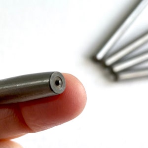 Pu&ograve; includere: Primo piano di un'asta di metallo argentata con un piccolo foro all'estremit&agrave;.