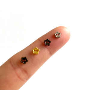 May include: Four star-shaped buttons in different colors: silver, black, gold, and bronze. The buttons have two holes each.