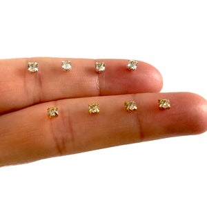 Könnte beinhalten: Nahaufnahme von sieben kleinen, klaren Strasssteinen, einige mit goldenen Fassungen, auf einem Finger angeordnet.