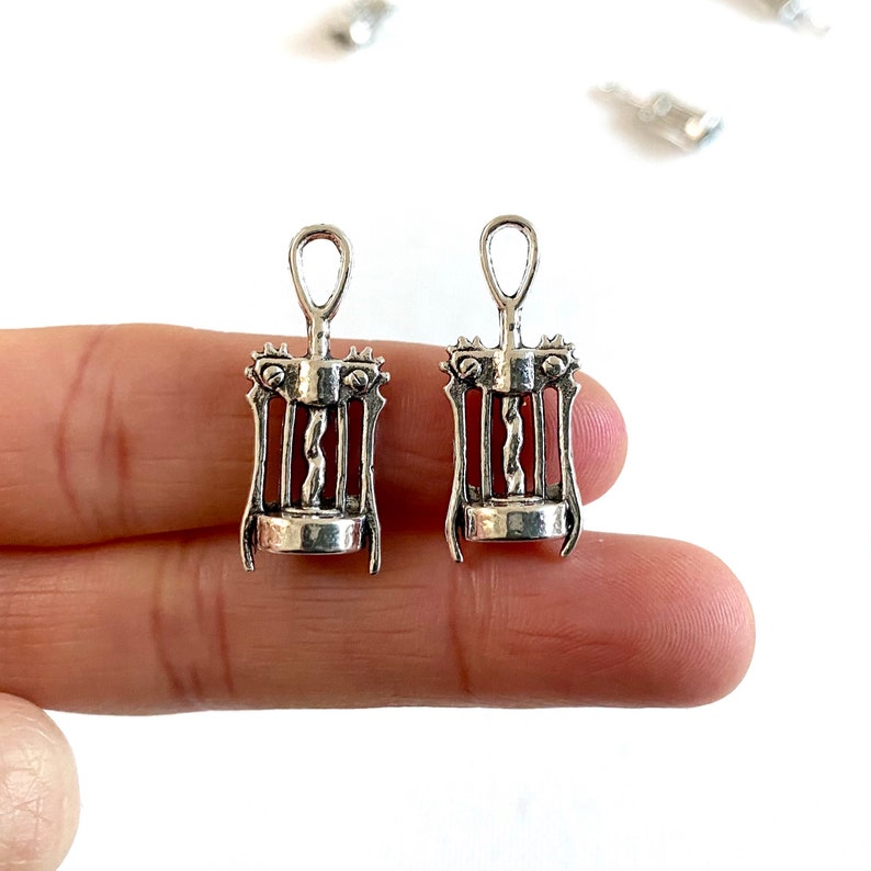 K&ouml;nnte beinhalten: Zwei silberfarbene Korkenzieher-Anh&auml;nger aus Metall. Die Anh&auml;nger sind mit einem Korkenzieher-Design verziert und haben oben eine &Ouml;se zum Anbringen an einer Halskette oder einem Armband.