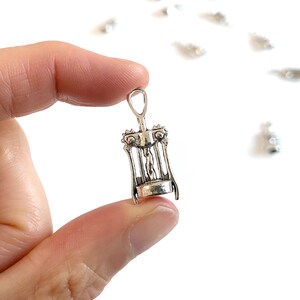K&ouml;nnte beinhalten: Ein silberfarbener Korkenzieher-Anh&auml;nger aus Metall mit detailliertem Design. Der Anh&auml;nger ist klein und zart und eignet sich perfekt, um einer Halskette oder einem Armband einen Hauch von Verspieltheit zu verleihen.