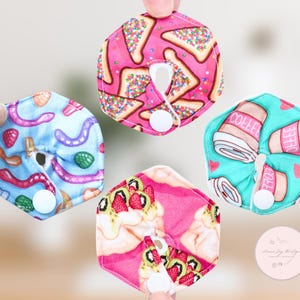 Puede incluir: Cuatro protectores de lactancia hexagonales con varios diseños. Uno tiene un fondo rosa con tostadas y chispas, otro tiene un fondo azul con gusanos coloridos, un tercero tiene un fondo rosa con fresas y el último tiene un fondo turquesa con tazas de café.