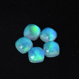 Op de afbeelding: Zes iriserende blauwe en groene edelsteen cabochons in een vierkante vorm.