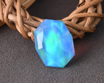 May include: A blue and green iridescent gemstone with a faceted octagonal shape.