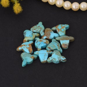 Può includere: Un gruppo di 12 cabochon di turchese a forma di campanaccio. Le pietre sono un mix di colori blu e marroni.