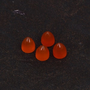 May include: Four orange carnelian cabochons in a teardrop shape.