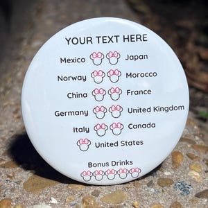 Puede incluir: Una pegatina redonda blanca con el texto "YOUR TEXT HERE" en la parte superior. La pegatina tiene una lista de países con un número correspondiente de cabezas de Minnie Mouse rosas junto a cada país. Los países enumerados son México, Japón, Noruega, Marruecos, China, Francia, Alemania, Reino Unido, Italia, Canadá y Estados Unidos. La pegatina también tiene el texto "Bonus Drinks" con una fila de cabezas de Minnie Mouse rosas debajo.