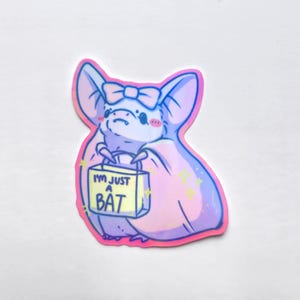 May include: A sticker featuring a cute cartoon bat with a pink and purple color scheme. The bat is holding a shopping bag that says "I'M JUST A BAT". The bat has a bow on its head and rosy cheeks.
