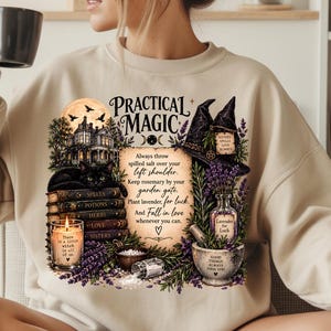 May include: A beige crewneck sweatshirt featuring a graphic print with the text Practical Magic, a house, a black cat, stacked books, a candle, a witch hat, lavender, and a mortar and pestle. The text includes instructions about salt, rosemary, and lavender.