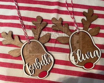 May include: Two wooden reindeer ornaments with red noses and white names. The ornament on the left says "Isabella" and the ornament on the right says "Olivia".