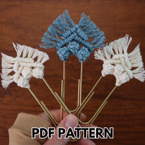 May include: Three macrame paper clips in cream and blue, with gold-colored metal clips. The macrame designs have a fringed edge and are held in a hand. The text "PDF PATTERN" is at the bottom of the image.