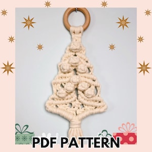 Könnte beinhalten: Cremefarbener Makramee-Weihnachtsbaum mit einem Holzring zum Aufhängen. Der Baum hat dekorative Knoten und eine Quaste am unteren Ende. Der Text "PDF PATTERN" ist unten im Bild zu sehen.