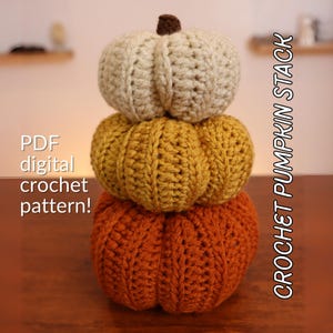 Peut inclure: Une pile de trois citrouilles au crochet en blanc, jaune et orange. Les citrouilles sont empilées les unes sur les autres, la plus grande en bas et la plus petite en haut. Le texte "CROCHET PUMPKIN STACK" est écrit verticalement sur le côté droit de l'image. Le texte "PDF digital crochet pattern!" est écrit sur le côté gauche de l'image.