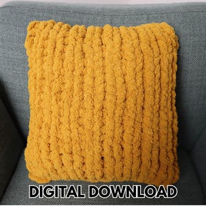 May include: A square, mustard-yellow knitted pillow with a textured, chunky knit design. The pillow is resting on a gray upholstered chair. The text "DIGITAL DOWNLOAD" is displayed at the bottom of the image.