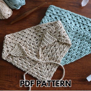 May include: Two crocheted items, one beige and one light blue, are displayed on a wooden surface. The beige item is folded and tied with a string. The text "PDF PATTERN" is at the bottom. Yarn and a crochet hook are also visible.
