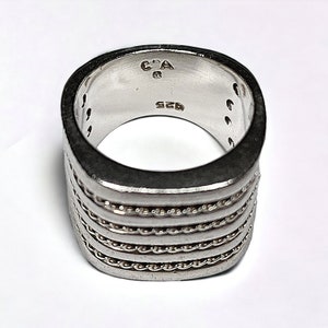 May include: Silver ring with a square band and a textured design. The ring is marked with "C.A. 925".