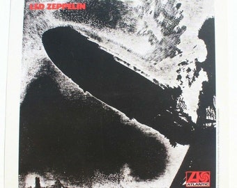 Peut inclure: Pochette d'album noir et blanc pour le premier album de Led Zeppelin. La pochette présente une image en noir et blanc d'un dirigeable sur un fond de ciel nuageux. Le titre de l'album "Led Zeppelin" est imprimé en rouge en haut de la pochette. Le logo d'Atlantic Records est en bas à droite.