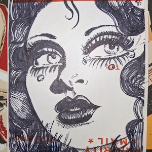 May include: Black and white line drawing of a woman's face with dramatic makeup and a long, flowing hairstyle. The drawing is done in a vintage style and has a slightly whimsical feel.