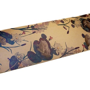 May include: A brown yoga mat with a repeating pattern of frogs, water lilies, and dragonfly silhouettes. The mat has the word "US" printed on the bottom left corner.