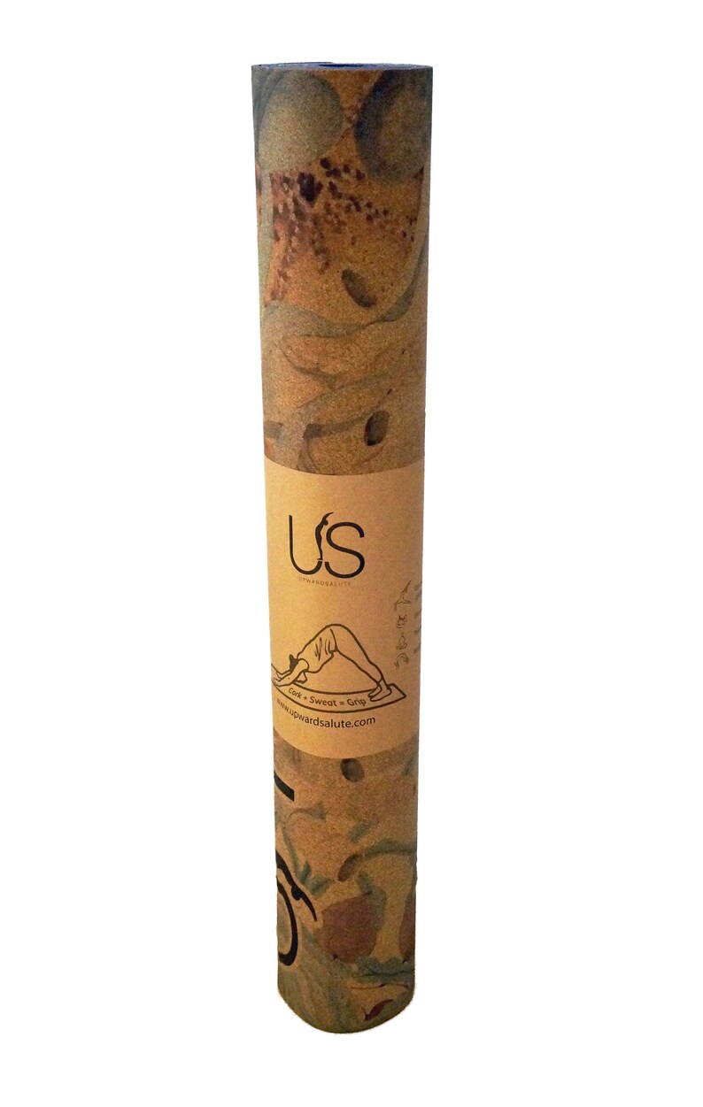 May include: A rolled-up yoga mat with a brown and tan patterned design. The mat is labelled "US" and "Upwards Salute" with the text "Core + Sweat = Grip" and a website address.