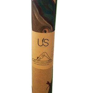May include: Rolled up cork yoga mat with a green edge. The mat has a printed design of a dragonfly and the text "US Upwardsalute Cork + Sweat + Grip www.upwardsalute.com".