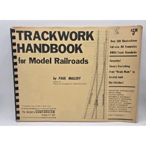May include: A vintage "Trackwork Handbook for Model Railroads" book by Paul Mallery. The cover is tan with black text and illustrations of model railroad tracks. The book includes over 300 illustrations and covers various aspects of model railroading.