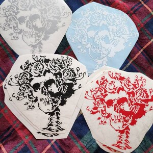 May include: Four skull and rose designs on white paper. The designs are in black, red, gray, and white. The designs are all the same, but in different colors.