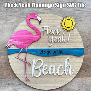 Może przedstawiać: Okrągły drewniany znak z napisem "Flock yeah! Let's go to the Beach" białymi literami. Różowy flaming z niebieską linią wody znajduje się po lewej stronie znaku. Żółte słońce znajduje się po prawej stronie znaku.