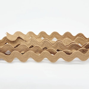 May include: A close-up of a brown wavy trim. The trim is made of a soft, flexible material and has a slightly textured surface.