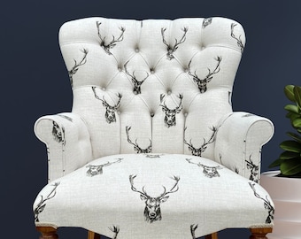Armchair chair seat covered in a natural fabric with stag deer animal print. brown